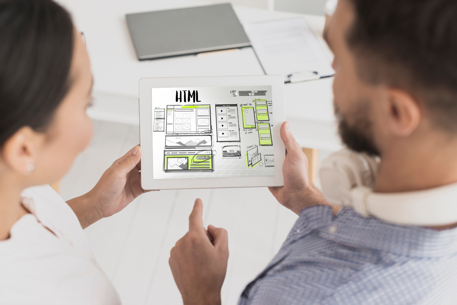 Deux personnes regardant une tablette avec un wireframe, illustrant la planification d’un site internet.